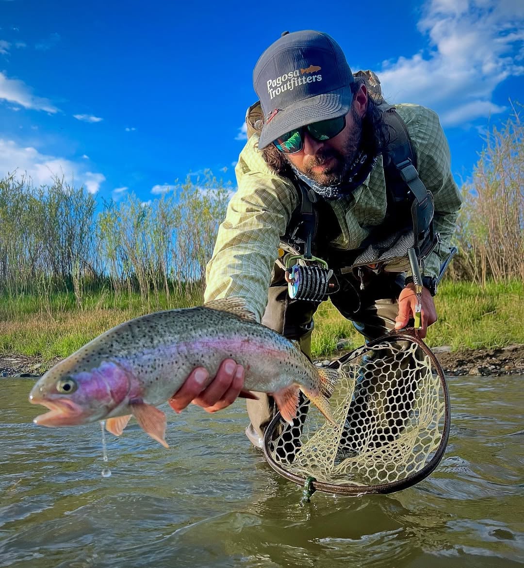 Guide holding a rainbow trout on private water near Pagosa Springs